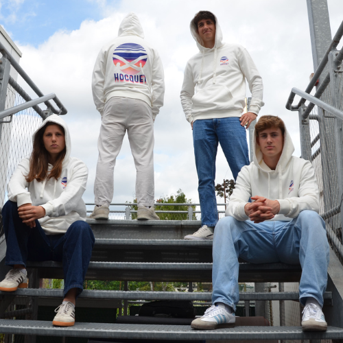 Image of a group wearing cream-colored HOCQUET hoodies. Sitting on a staircase